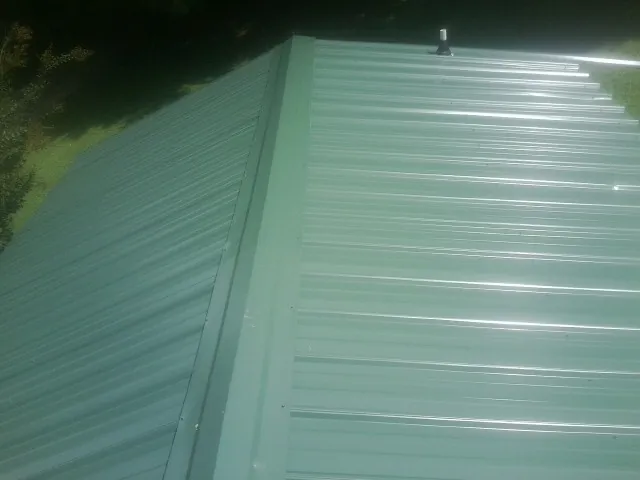 New green metal panels meeting at the ridge of a roof — Flat Roof Repair work by our crew in Frackville