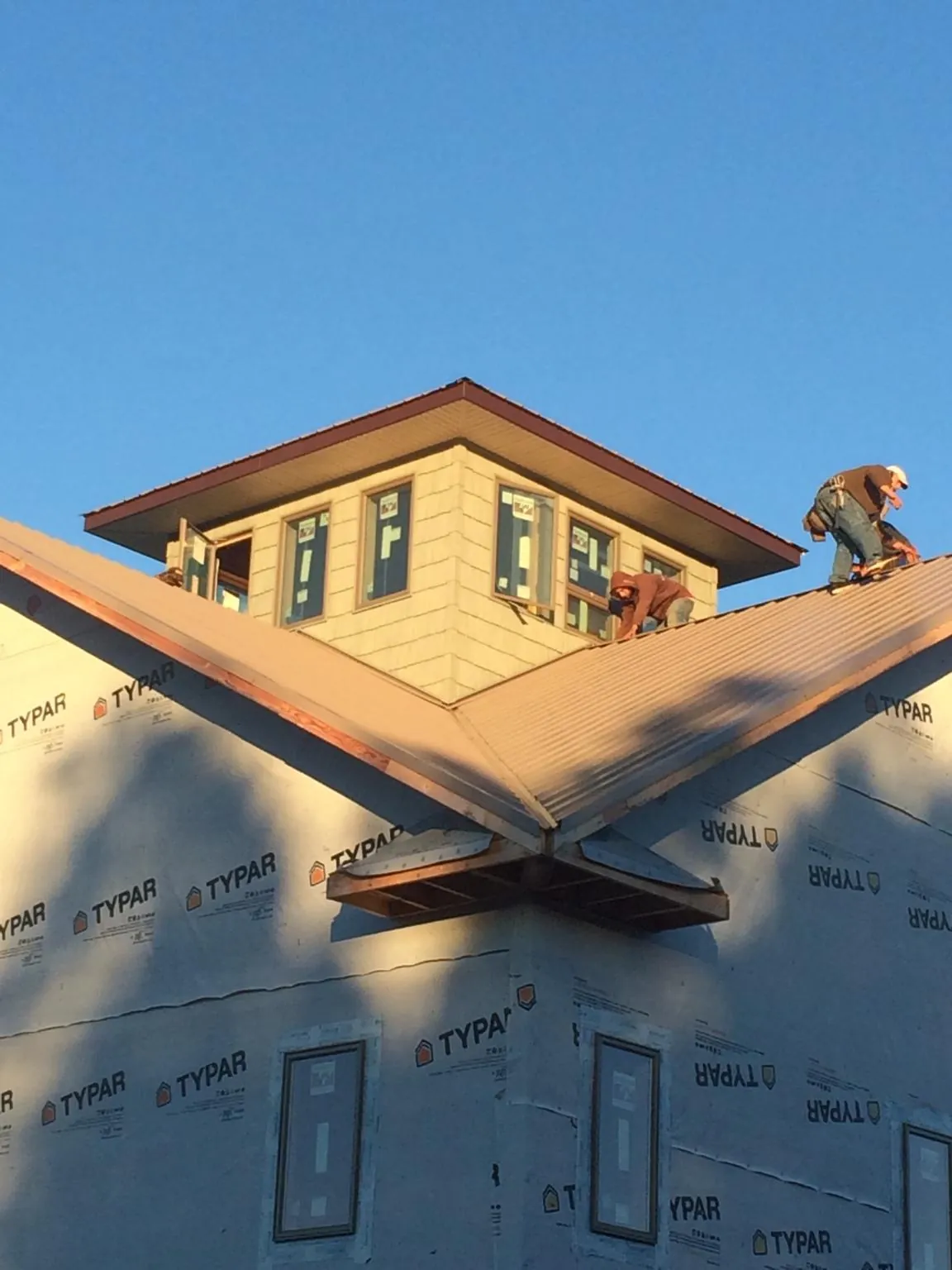 Roofers working around a rooftop cupola on a new metal roof at sunset — Roof Waterproofing in Frackville by Roofing Brothers